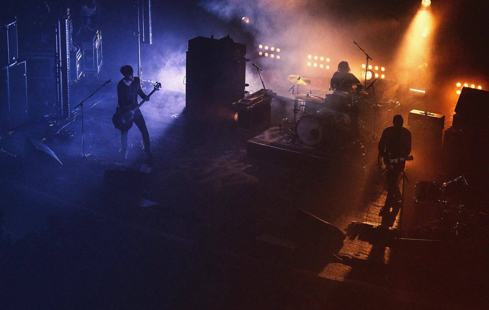 Band playing on a hazy stage seen from above, lit in violet and amber