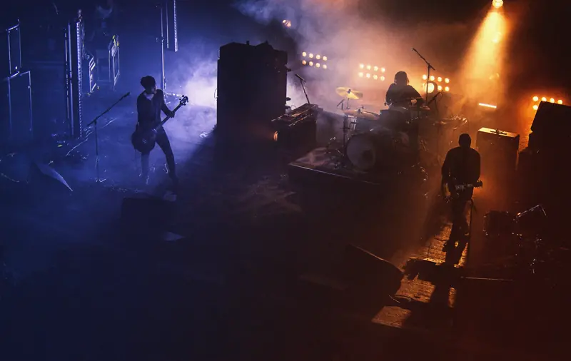 Band playing on a hazy stage seen from above, lit in violet and amber