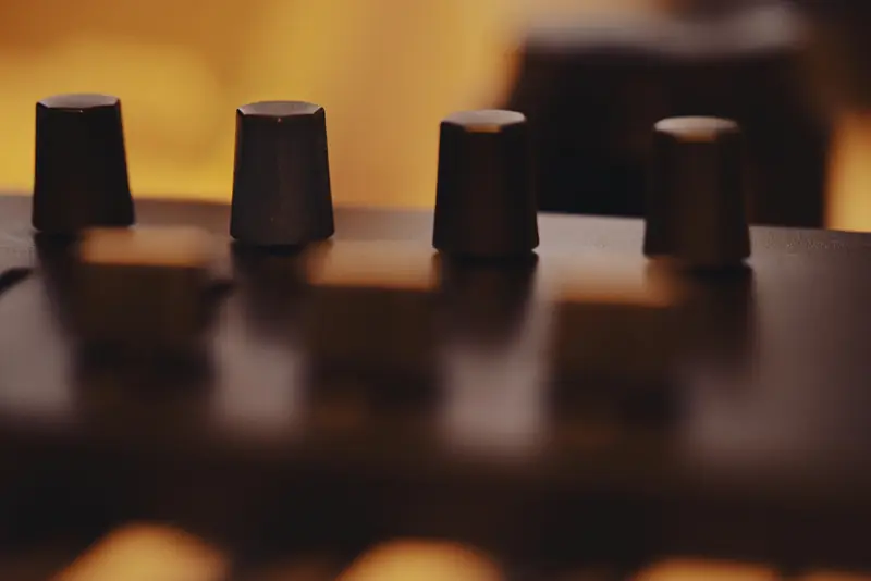 Four dark synthesizer control knobs in warm amber ambient light